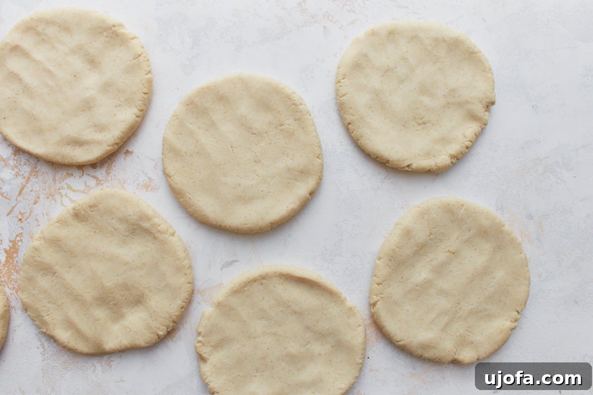 Authentic Mexican Gorditas 8 Several flattened raw gordita disks of masa dough neatly laid out on a white countertop, showcasing their uniform shape and thickness before cooking.