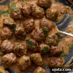 A smaller square image of Keto Swedish meatballs in a creamy sauce garnished with fresh parsley in a skillet.