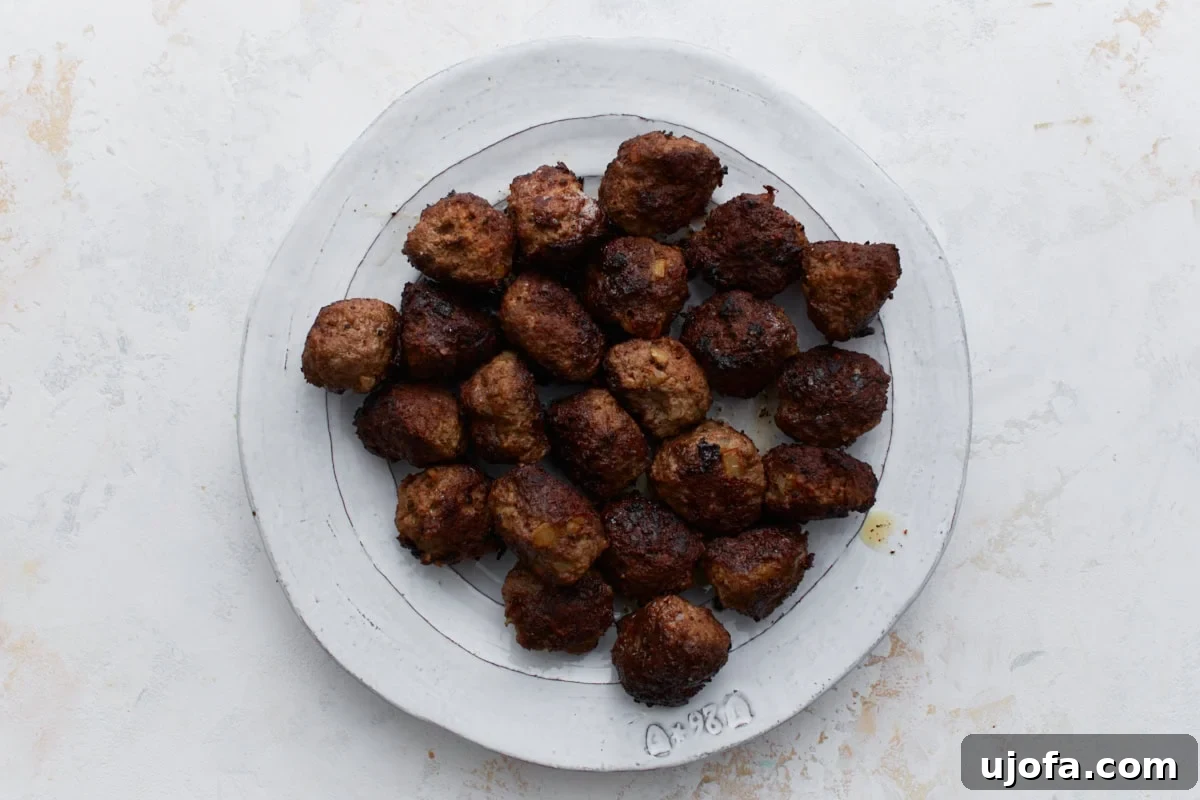 A selection of browned, perfectly cooked meatballs resting on a plate, having been pan-fried to a rich golden-brown hue.