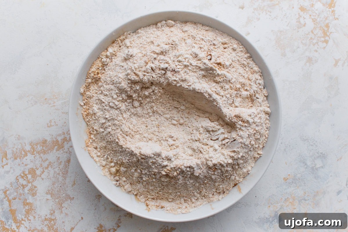 A white bowl filled with a blended mixture of gluten-free flour and warm spices like cinnamon and ginger on a light background.