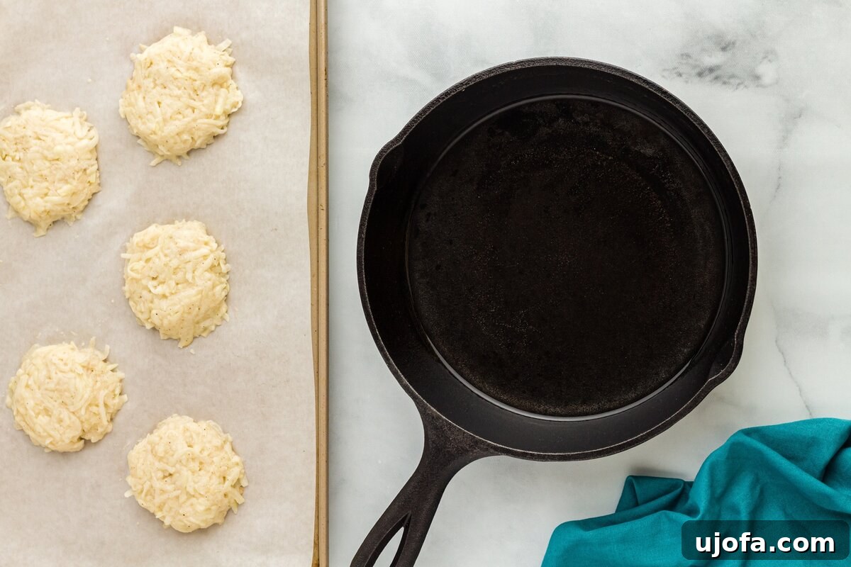 Neatly shaped latke patties, approximately half an inch thick, laid out on a parchment-lined baking sheet, prepared for frying.