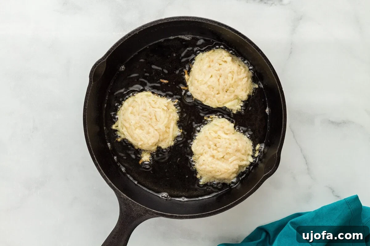 Several golden-brown latke patties sizzling vigorously in hot vegetable oil within a well-seasoned cast-iron skillet, indicating optimal frying temperature.