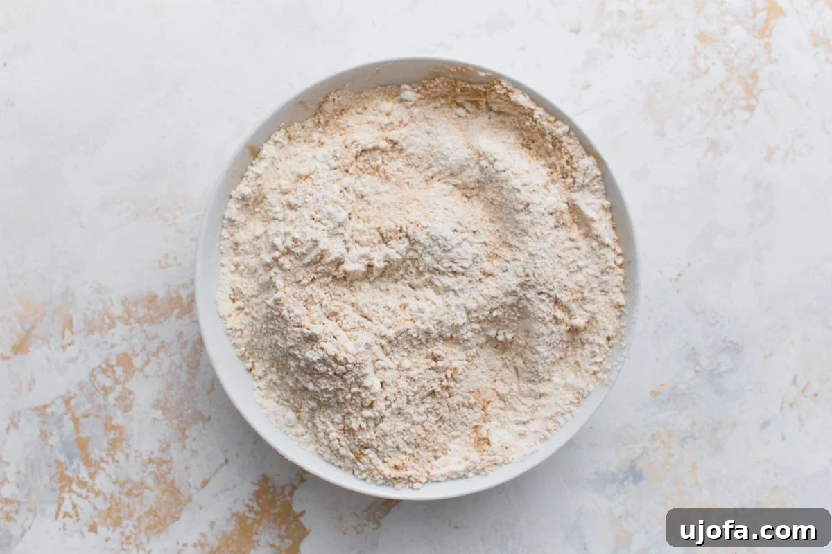 Spiced Gluten-Free Ginger Snaps 5 A medium bowl containing gluten-free flour, ground ginger, cinnamon, cloves, baking soda, and salt, freshly whisked.