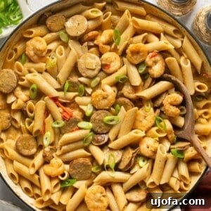 cajun shrimp and sausage pasta in a skillet topped with green onions
