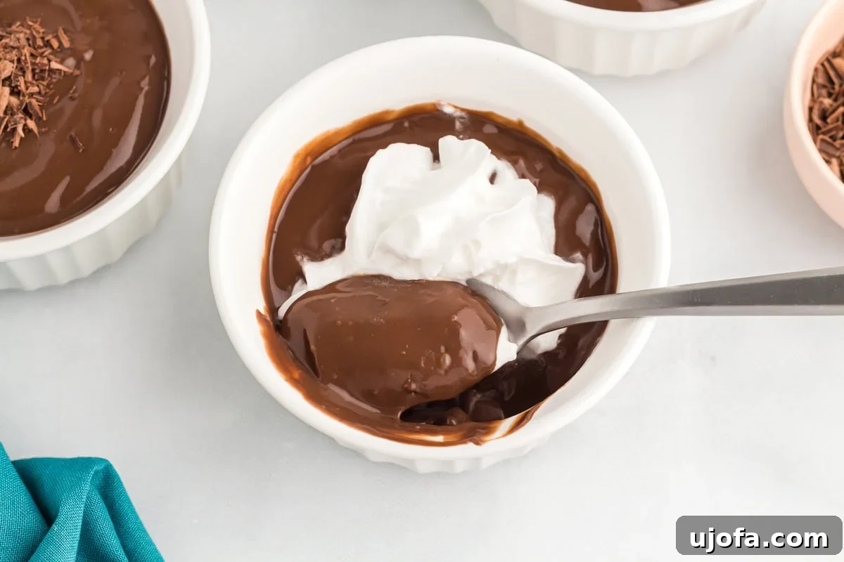 Spoonful of creamy dairy-free chocolate pudding topped with coconut whipped cream, ready to enjoy.