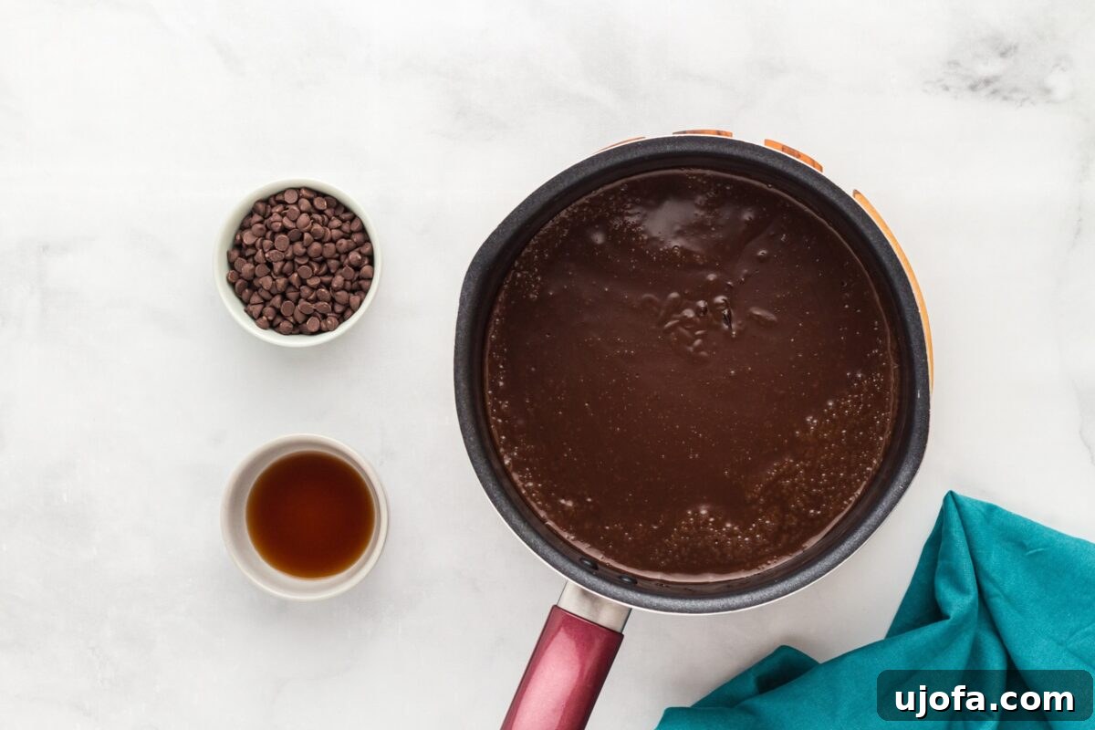 Chocolate pudding mixture beginning to simmer in a saucepan, with ingredients laid out beside it.