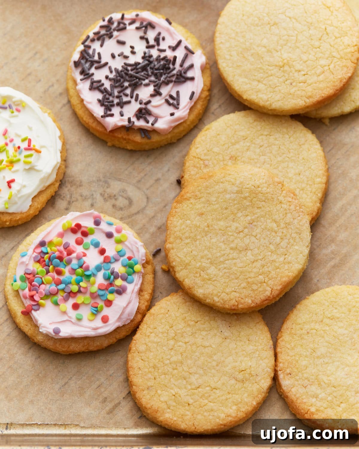 Frosted and unfrosted almond flour sugar cookies arranged on a parchment-lined baking sheet.