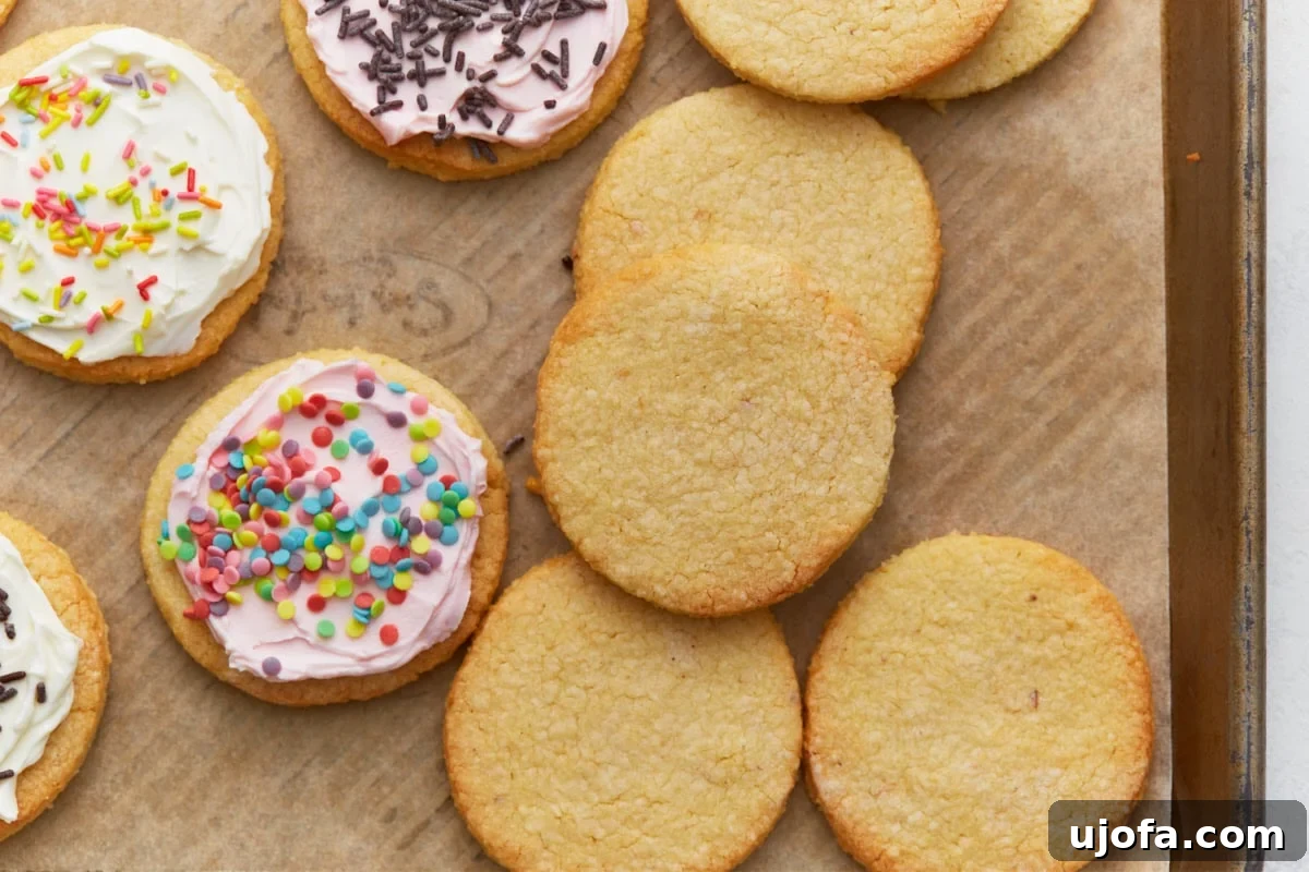 Frosted and unfrosted almond flour sugar cookies arranged on a parchment-lined baking sheet.