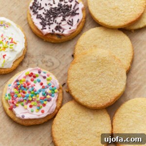 Frosted and unfrosted almond flour sugar cookies arranged on a parchment-lined baking sheet.