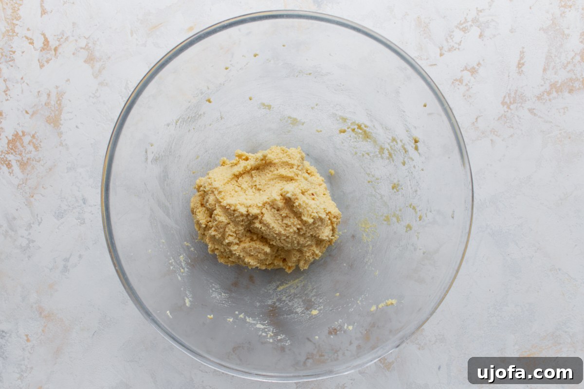 Almond flour sugar cookie dough combined and formed into a soft ball in a glass bowl.