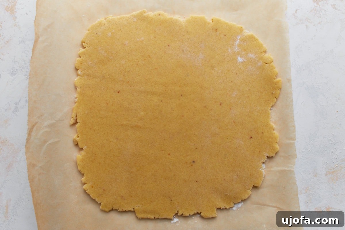 Chilled almond flour sugar cookie dough rolled out between parchment paper.