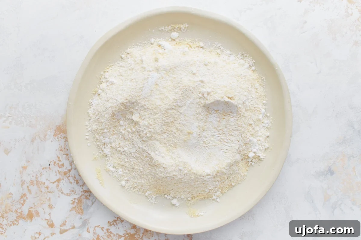 A white plate filled with a sifted mixture of almond flour and powdered sugar, ready for macaron batter.