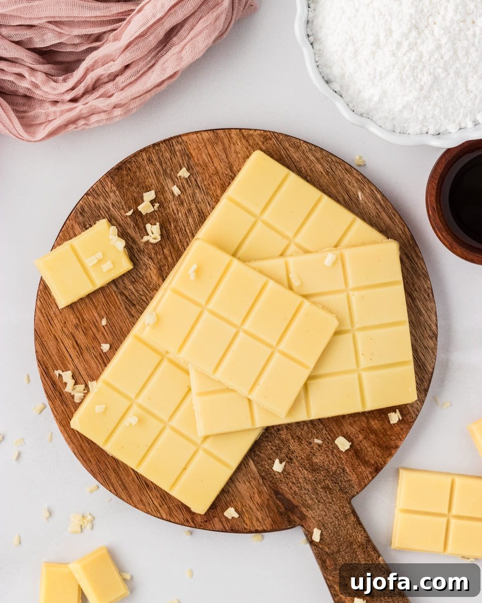 Vegan white chocolate bars stacked on a wooden board with small shaved pieces scattered around.