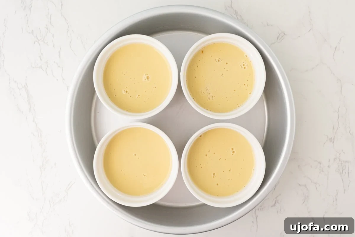 Plant Based Crème Brûlée Bliss 9 Smooth dairy-free custard mixture perfectly divided into four white ramekins, nestled in a baking dish with hot water.
