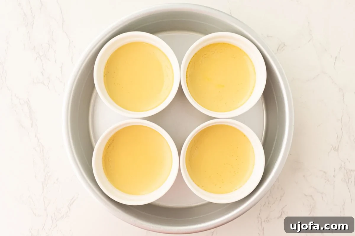 Plant Based Crème Brûlée Bliss 10 Baked dairy-free crème brûlée custards, pale yellow and lightly jiggling in their ramekins within the water bath, cooling down.