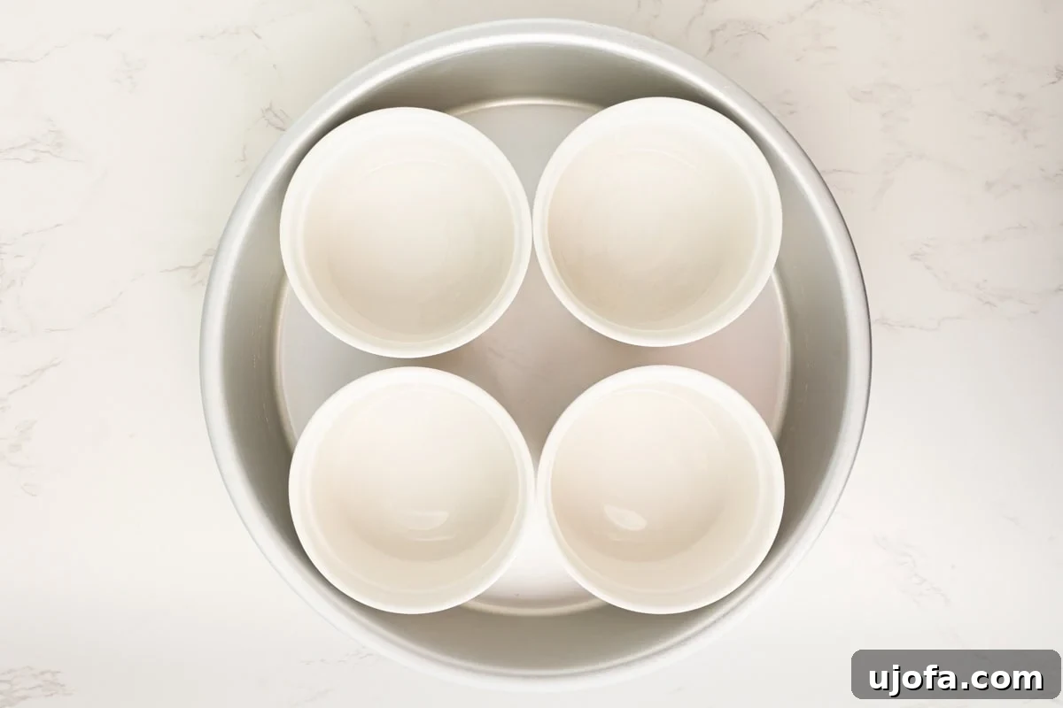 Plant Based Crème Brûlée Bliss 4 Four empty white ramekins arranged neatly in a round glass baking dish, ready for custard filling and a water bath.