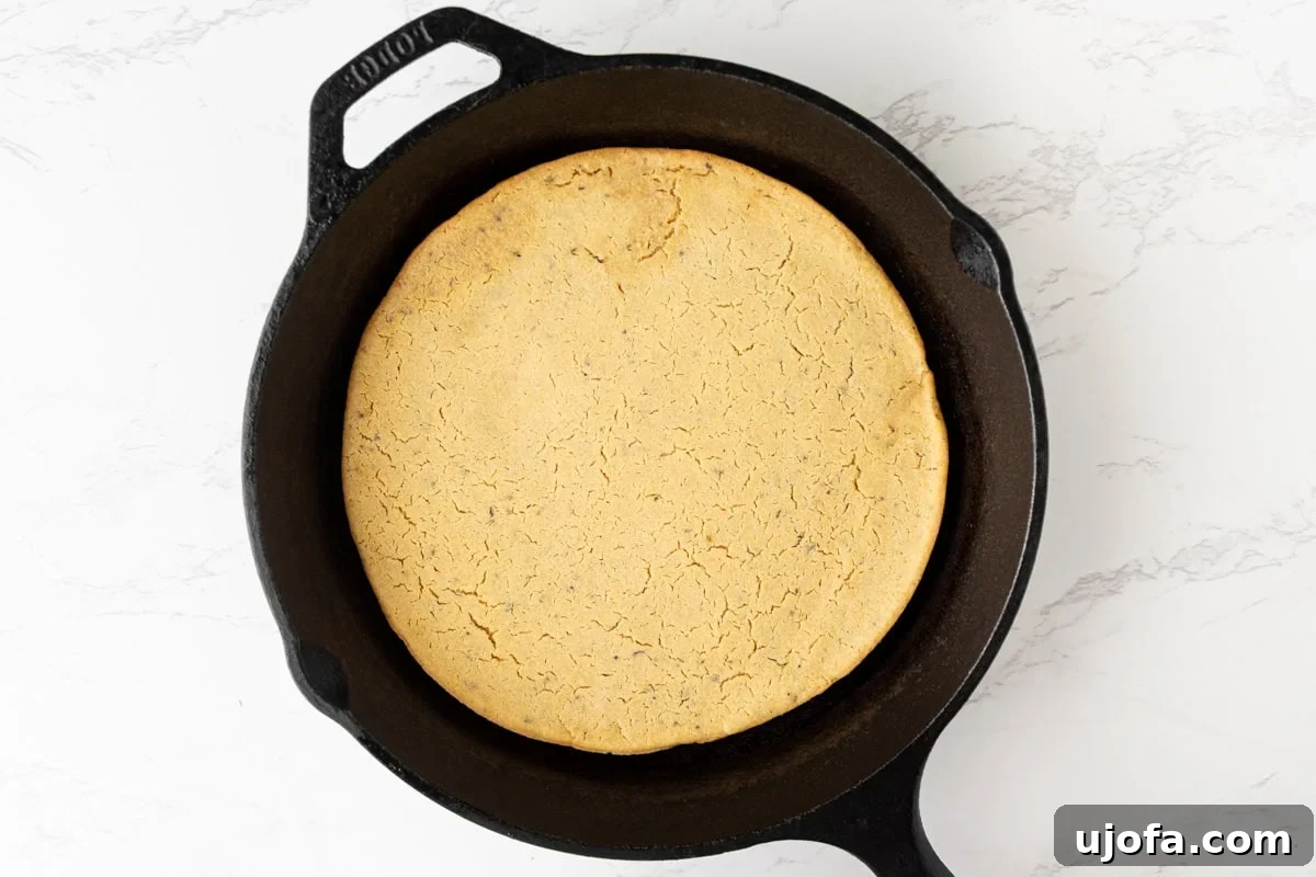Fully baked chickpea pizza crust in a cast iron pan with golden edges