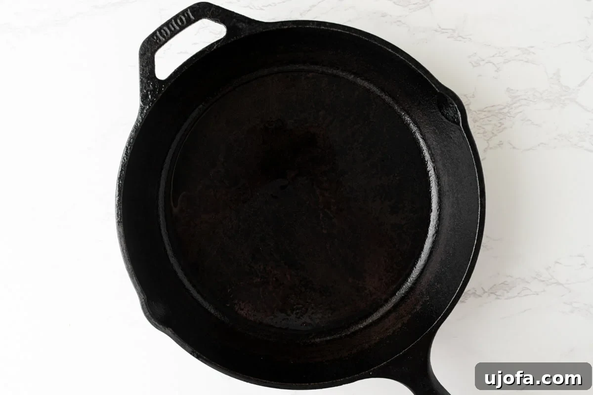 Empty cast iron skillet preheated and dusted with oil, on a light countertop