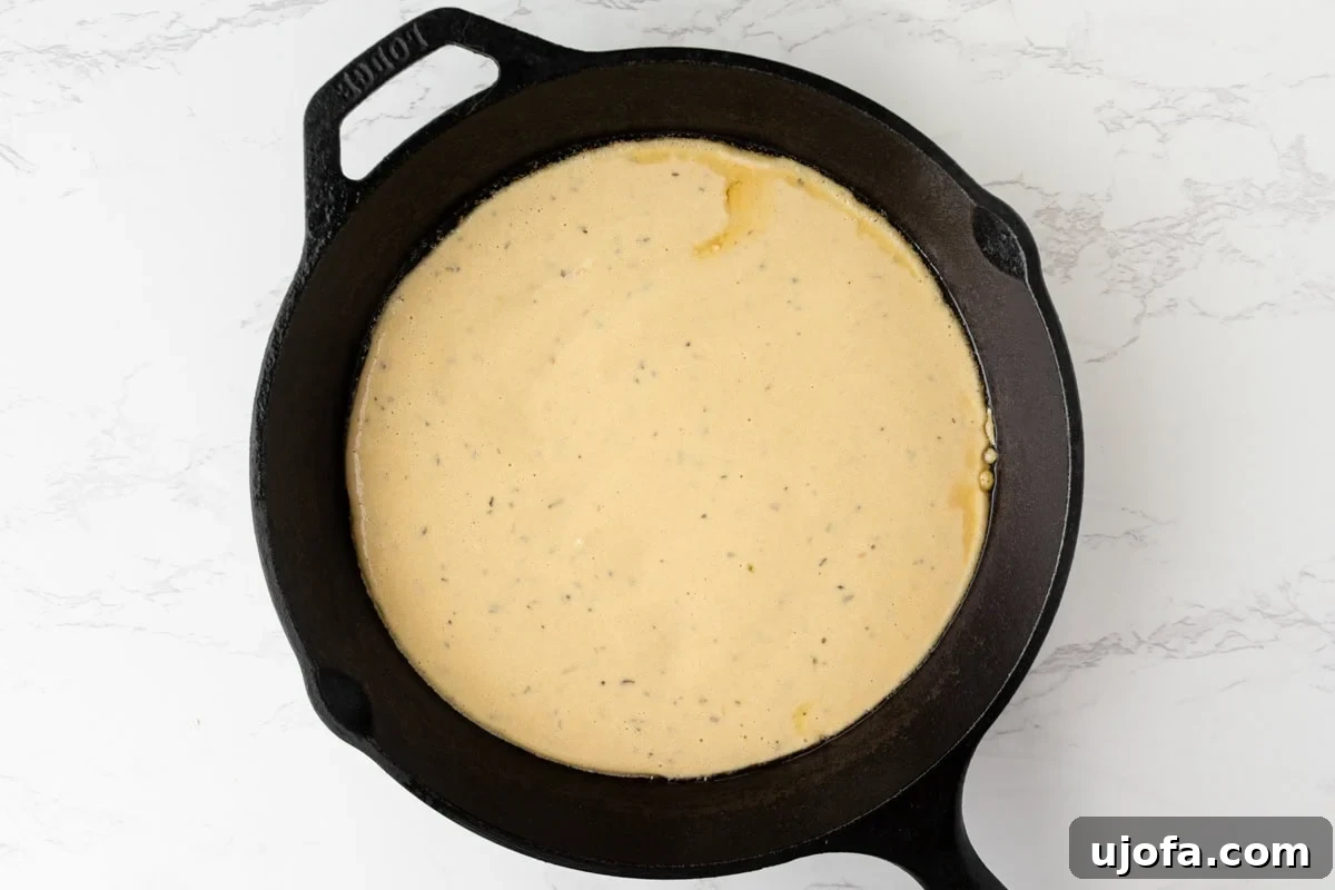 Chickpea pizza crust batter poured into a hot cast iron skillet
