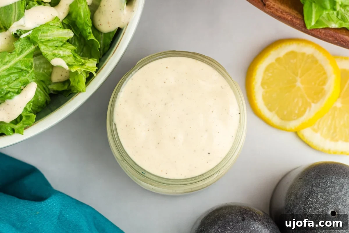 Creamy Dairy-Free Caesar Dressing 7 Small glass jar filled with creamy dairy-free Caesar dressing next to fresh romaine lettuce and lemon slices
