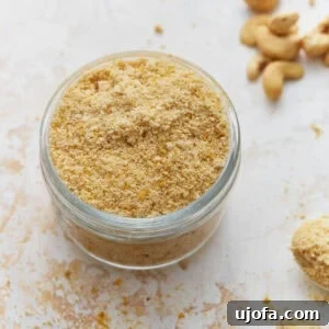 Jar filled with homemade vegan parmesan cheese made from cashews and nutritional yeast on a light countertop.
