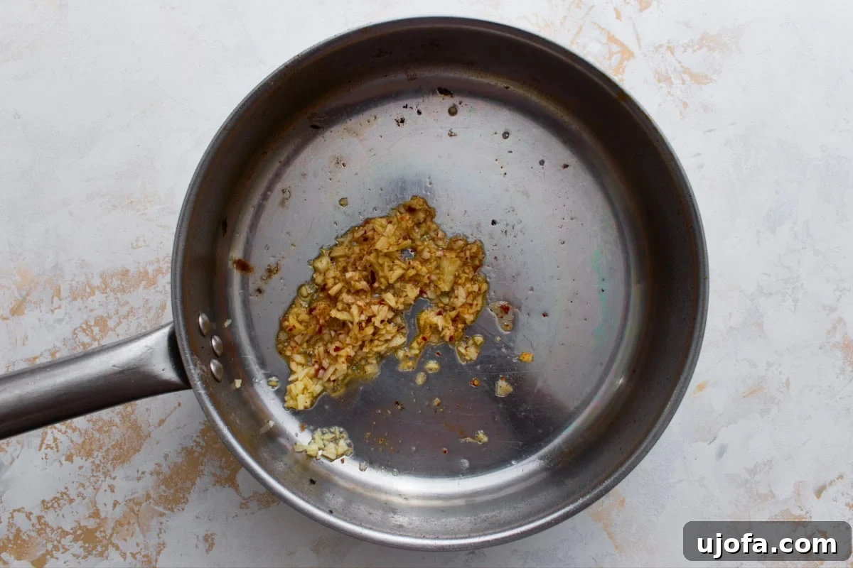 Minced garlic, ginger, and red pepper flakes sautéing in sesame oil in a skillet
