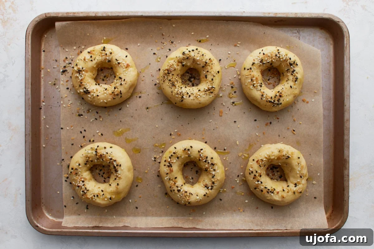 Perfect Keto Bagels 12 Unbaked keto bagels sprinkled with everything bagel seasoning on a parchment-lined baking sheet.