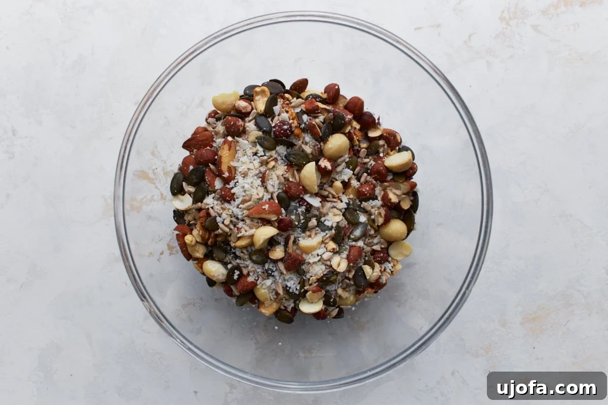 Ketogenic Granola Clusters 5 Unbaked keto granola ingredients in a glass bowl, including mixed nuts, seeds, and coconut flakes before mixing.