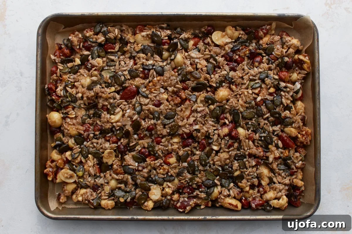 Ketogenic Granola Clusters 7 Keto granola mixture spread evenly on a parchment-lined baking sheet, ready for baking.