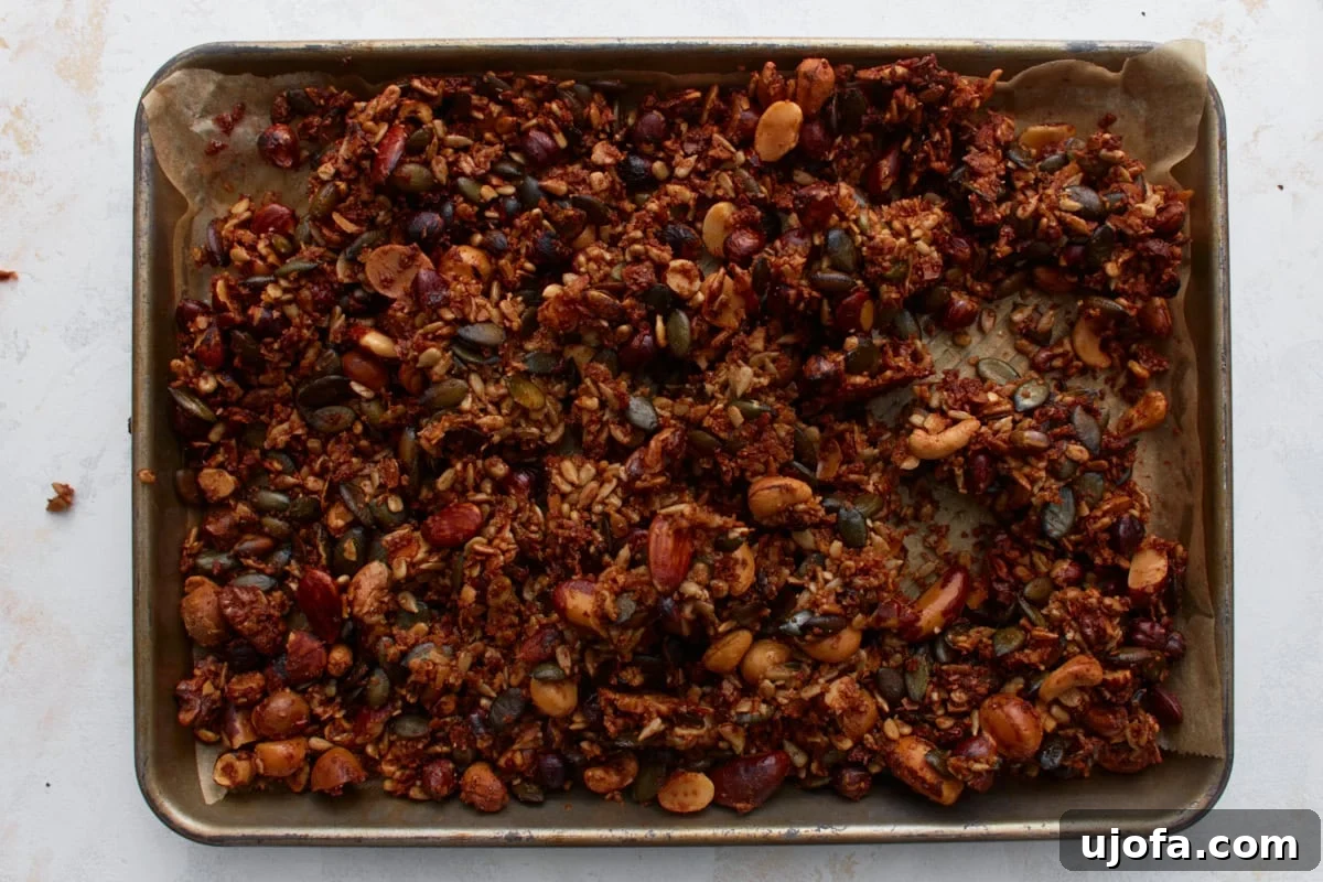 Ketogenic Granola Clusters 9 Freshly baked keto granola on a parchment-lined baking sheet, showing golden brown clusters of nuts and seeds after cooling, ready to be broken apart.