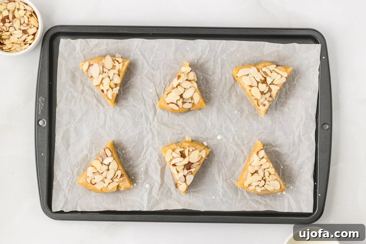 Tender Almond Scones 12 Unbaked almond flour scones topped with sliced almonds on parchment lined baking sheet