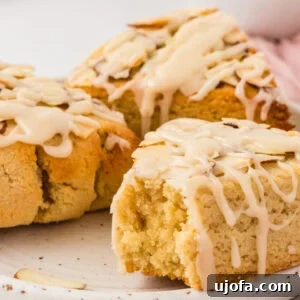 Close-up of almond flour scone with vanilla icing drizzle and sliced almonds showing soft crumb