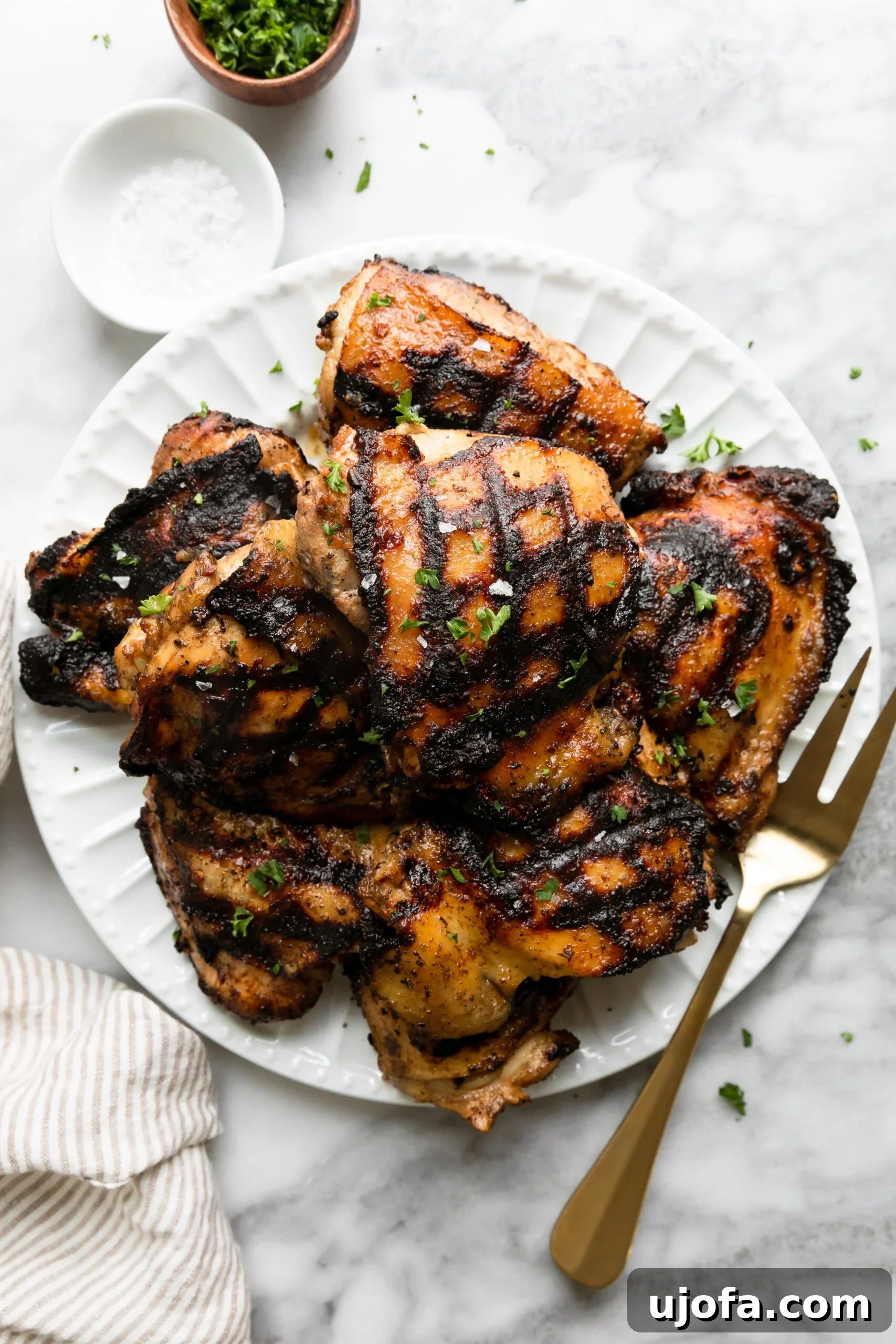 Juicy Keto Chicken Thighs with a Healthy Zesty Marinade 2 Grilled keto chicken thighs beautifully plated with a gold fork, showcasing their crispy skin and succulent interior.