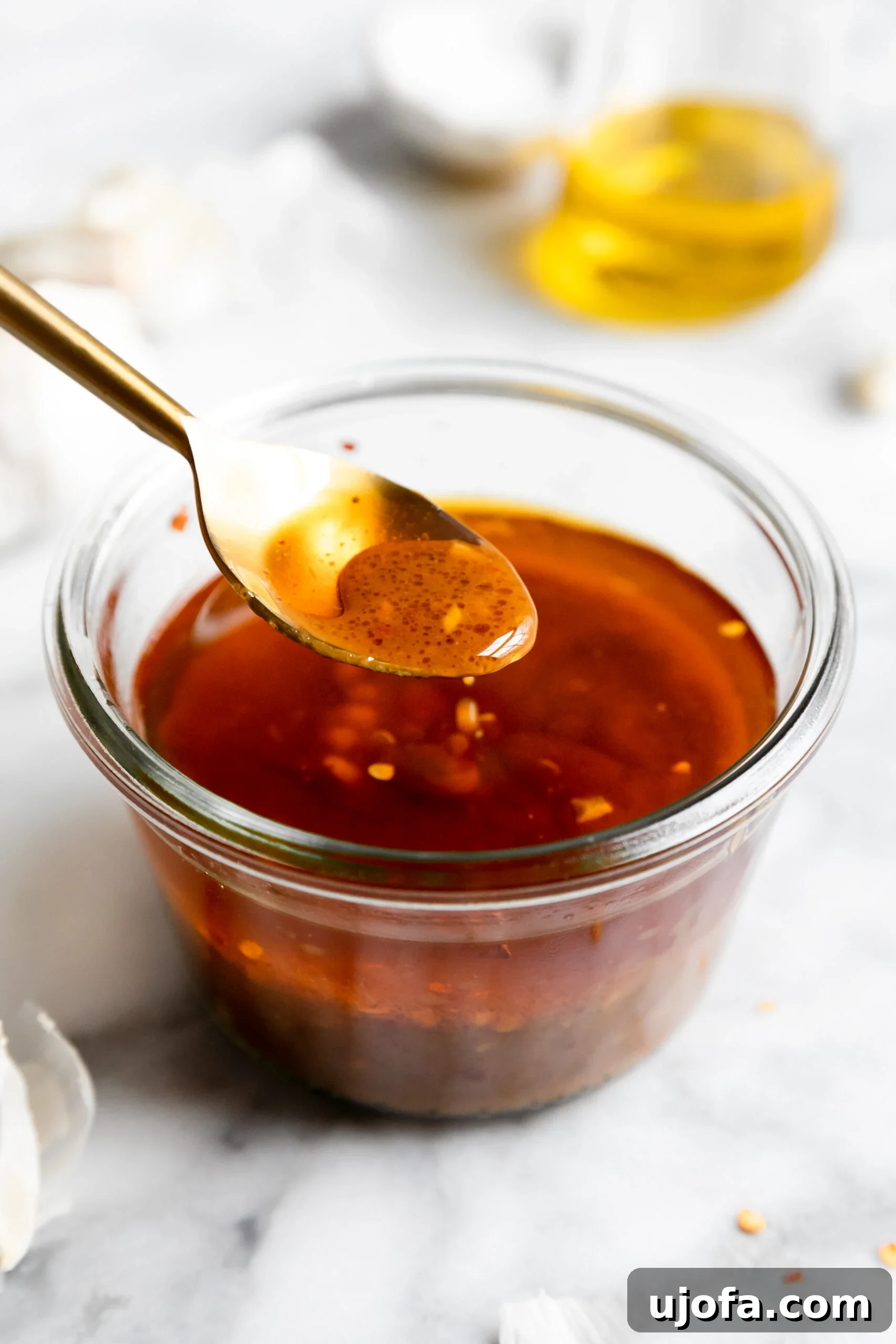Juicy Keto Chicken Thighs with a Healthy Zesty Marinade 4 A close-up of a small glass jar filled with the prepared chicken thigh marinade, with a gold spoon showing a delicious sample of the sauce.
