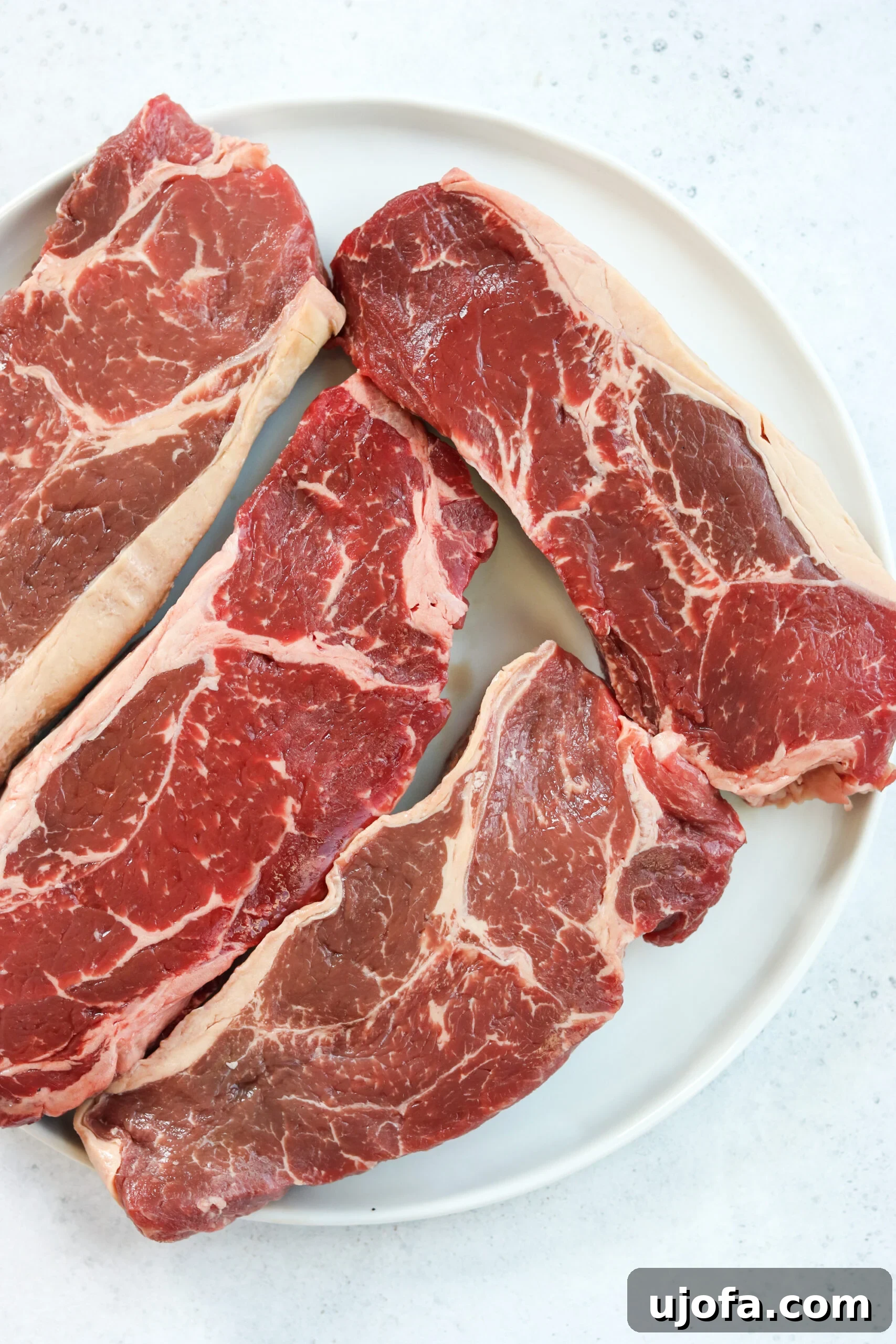 A selection of raw Australian grass-fed beef steaks, seasoned and ready for grilling, showcasing their lean, high-quality texture.