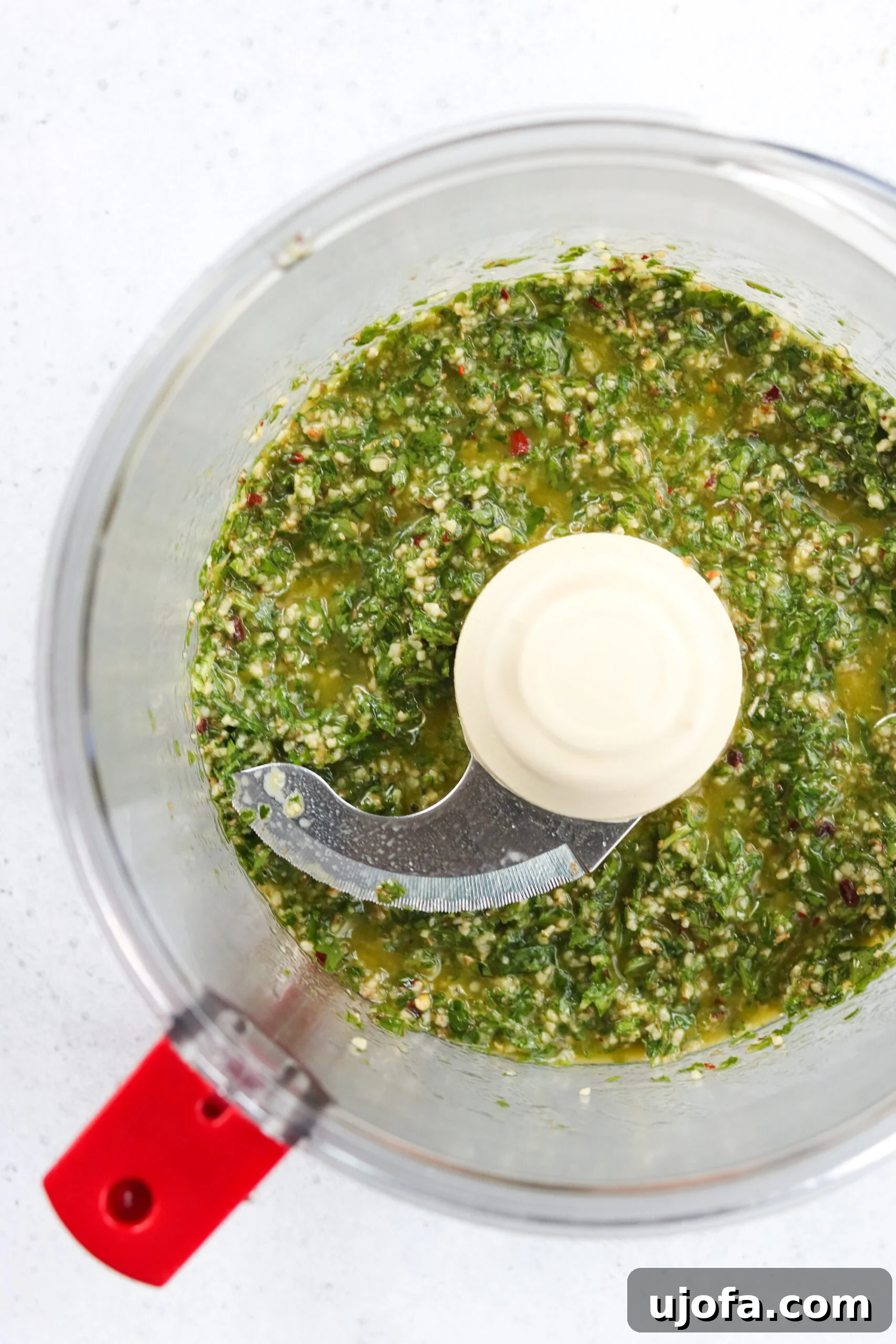 A vibrant green chimichurri sauce in a small bowl, garnished with fresh parsley and red pepper flakes, ready to be drizzled over grilled steak.