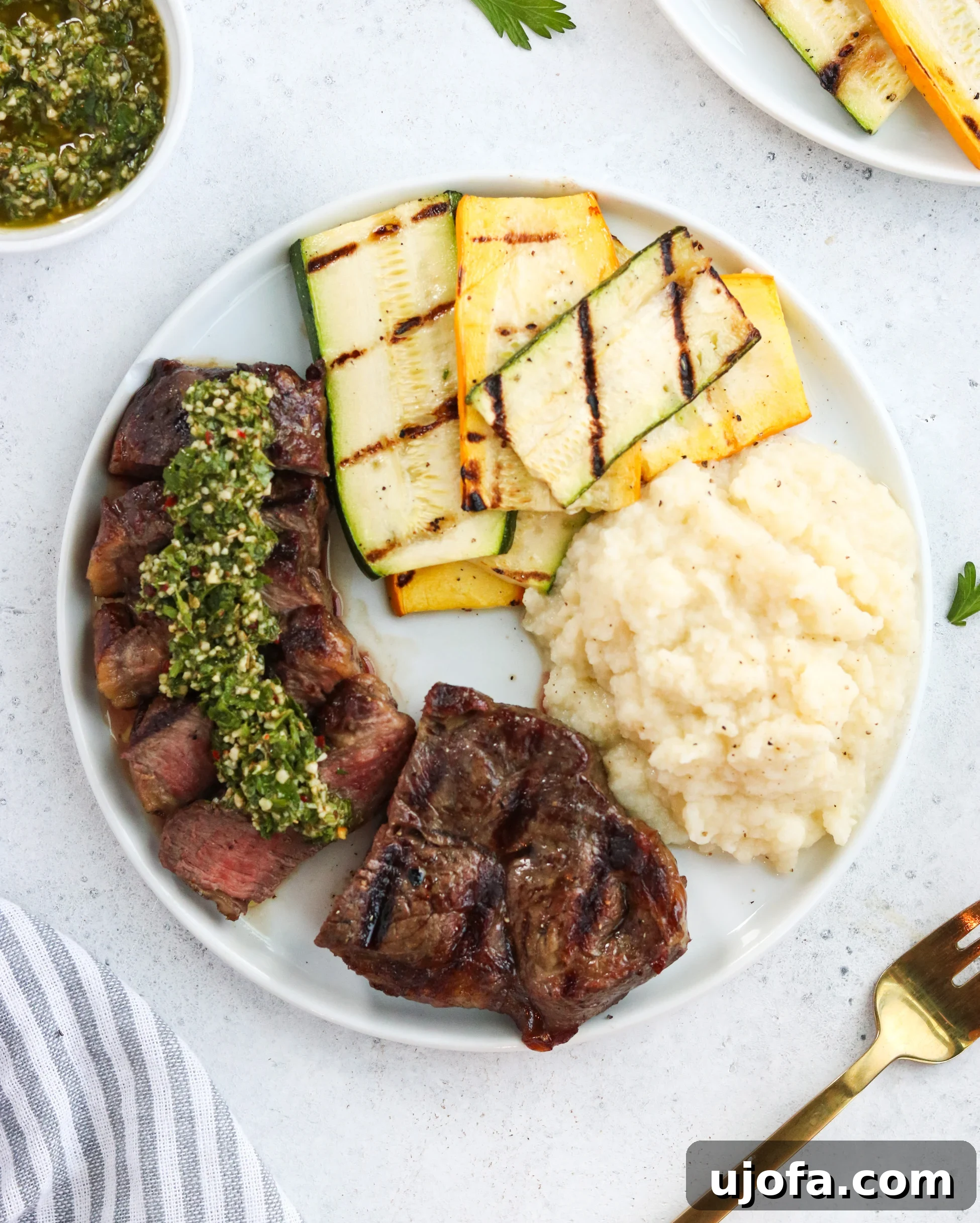 A beautifully plated Grilled New York Strip with Chimichurri Sauce, sliced and ready to serve, accompanied by fresh side dishes.
