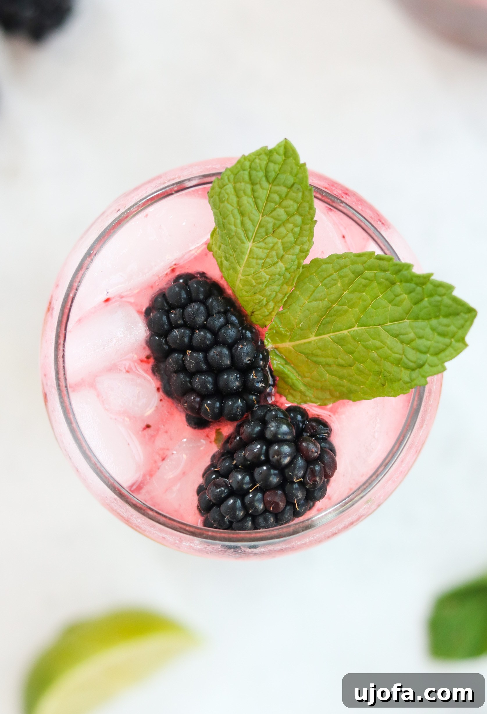 Ingredients laid out for a Blackberry Mojito: rum, lime, mint, blackberries, and honey syrup