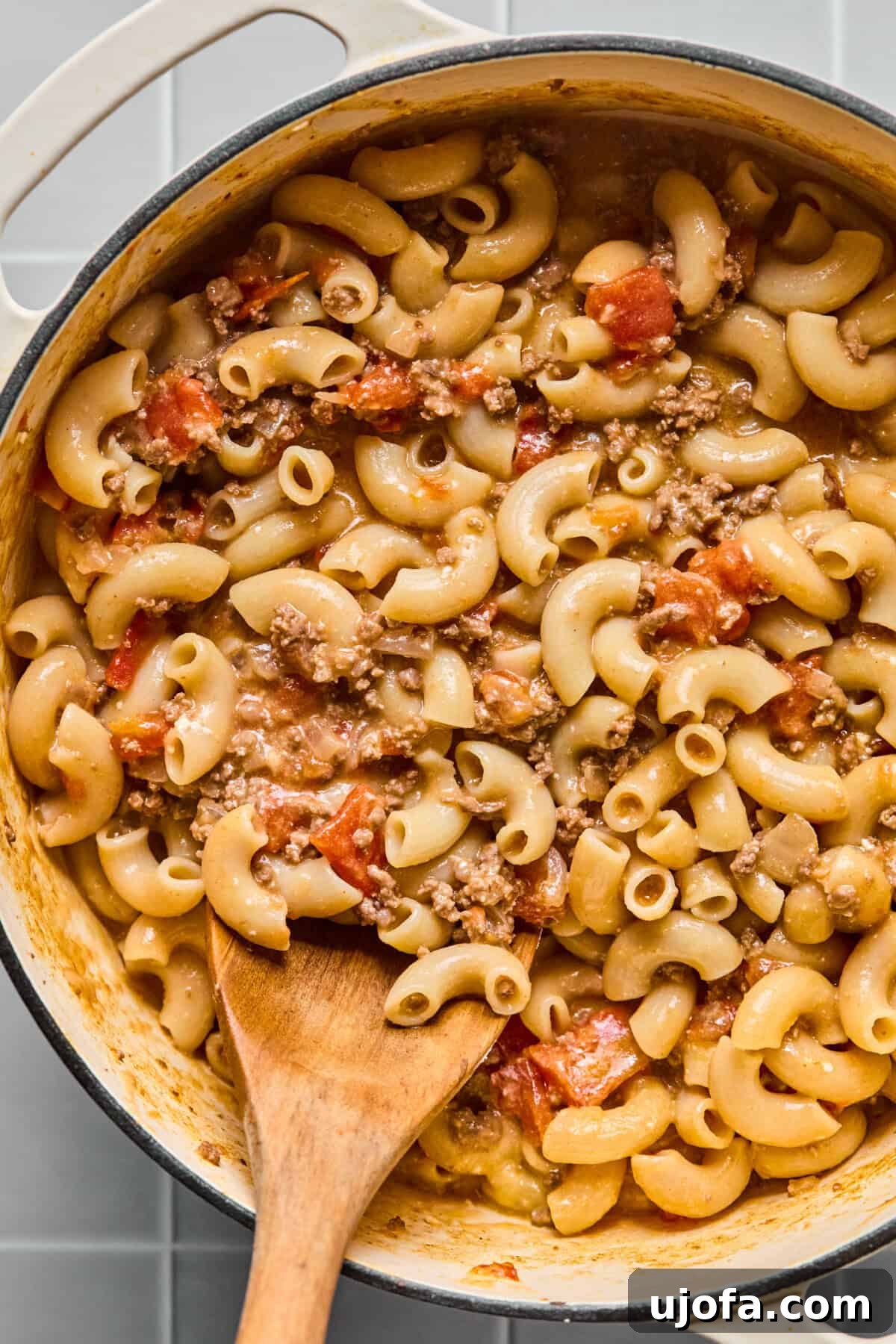 Finished one-pot gluten-free hamburger helper in a pot with a wooden spoon, ready to serve.