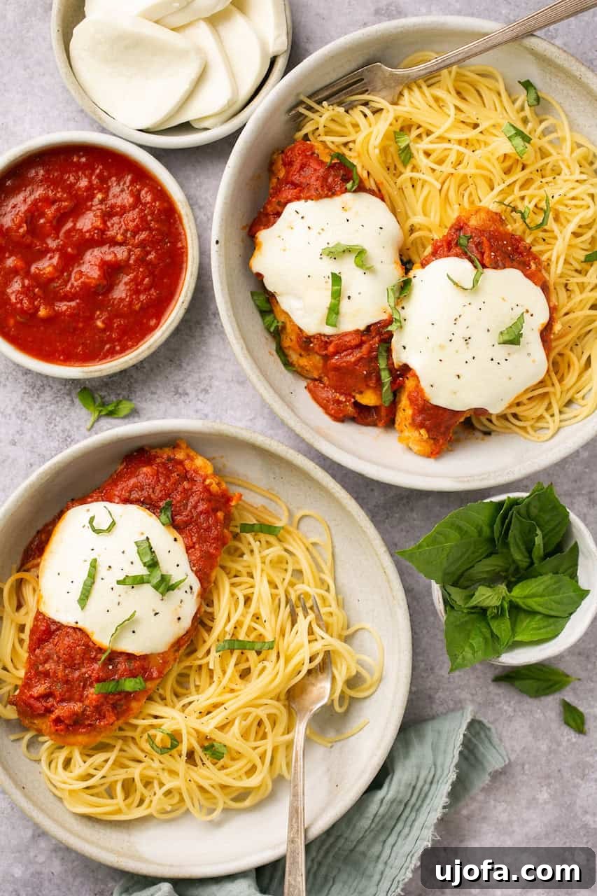 Two bowls of pasta topped with golden-brown chicken parmesan, garnished with fresh basil and surrounded by vibrant marinara sauce and melted cheese.
