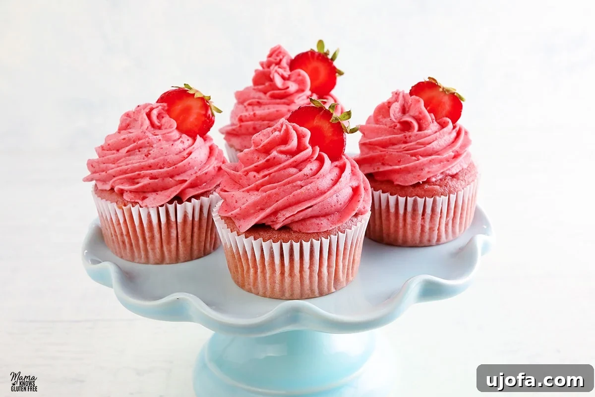 Fresh gluten-free strawberry cupcakes on a blue cake stand, adorned with strawberry buttercream
