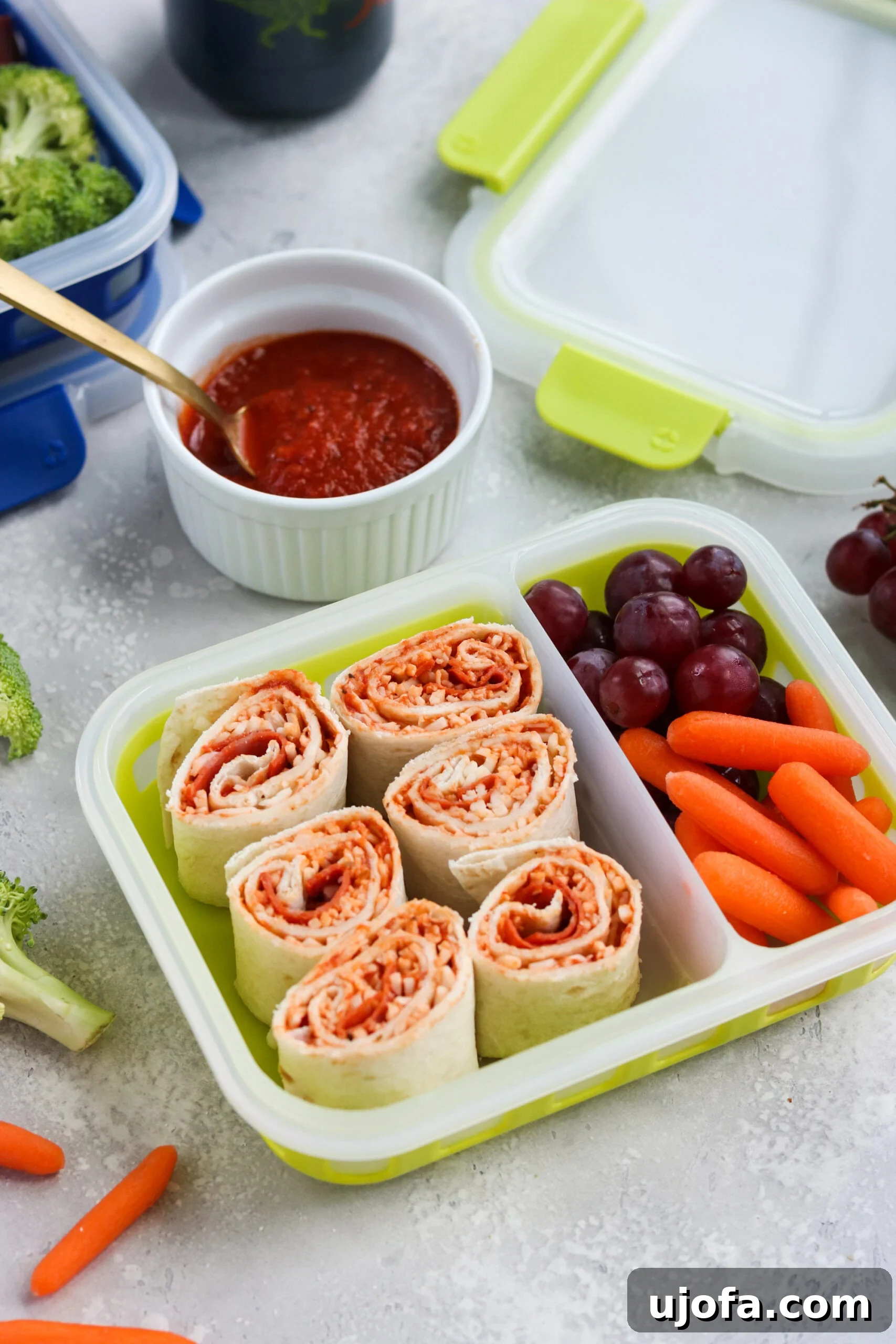 A child's lunchbox featuring Pizza Pinwheels alongside fresh berries and other healthy snacks, ready for school.