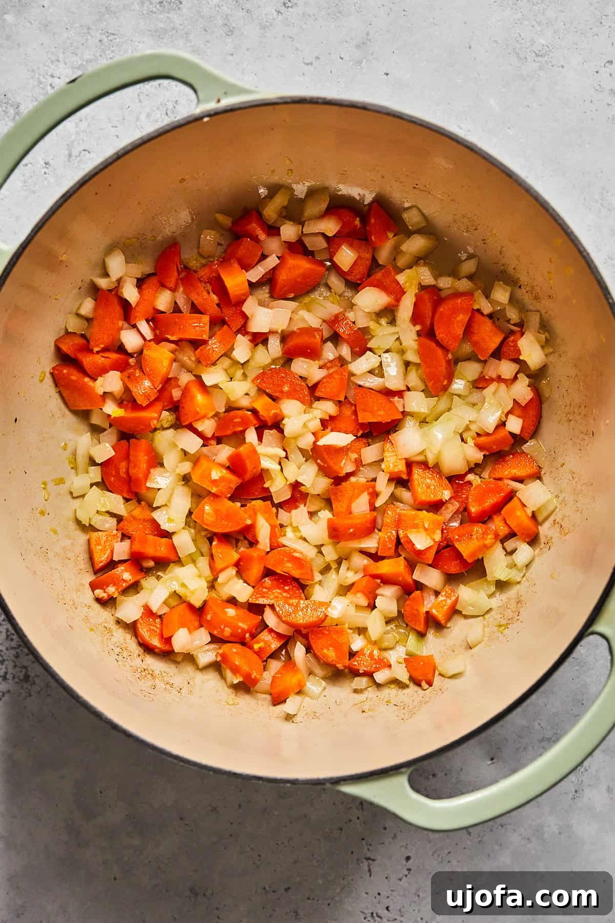 Creamy Dairy-Free Bacon Cheeseburger Soup 6 Diced onions and carrots simmering in a pot with aromatics, turning translucent and fragrant.