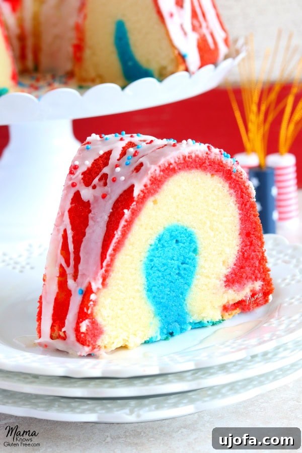 A slice of Gluten-Free Firecracker Almond Bundt Cake revealing distinct red, white, and blue layers, covered in a sweet vanilla almond glaze, ready for a 4th of July celebration. Also suitable for dairy-free diets.