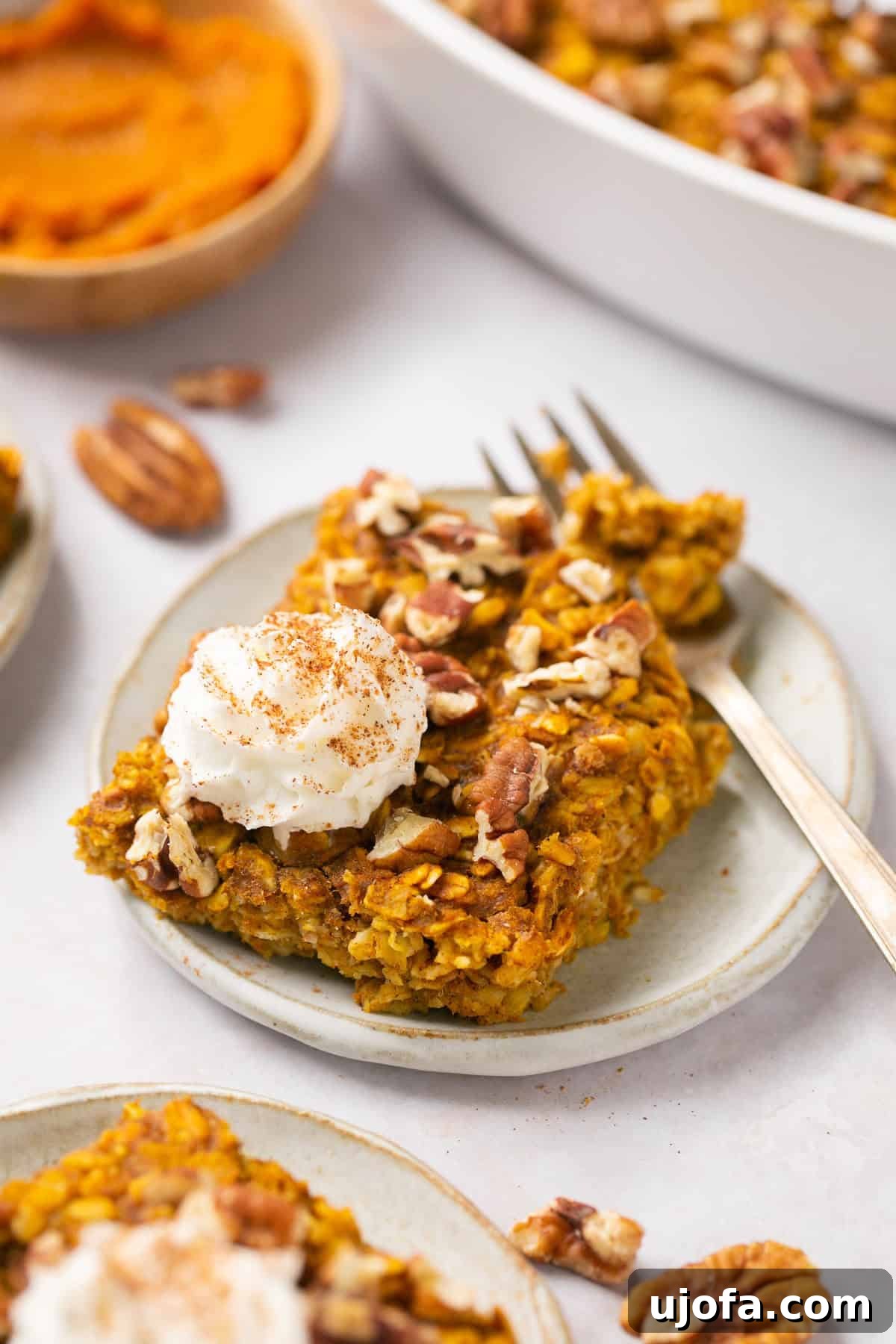 A bowl of pumpkin baked oatmeal topped with whipped cream and a fork, ready to be enjoyed.