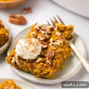 pumpkin baked oatmeal on a plate with a dollop of whipped cream and a gold fork
