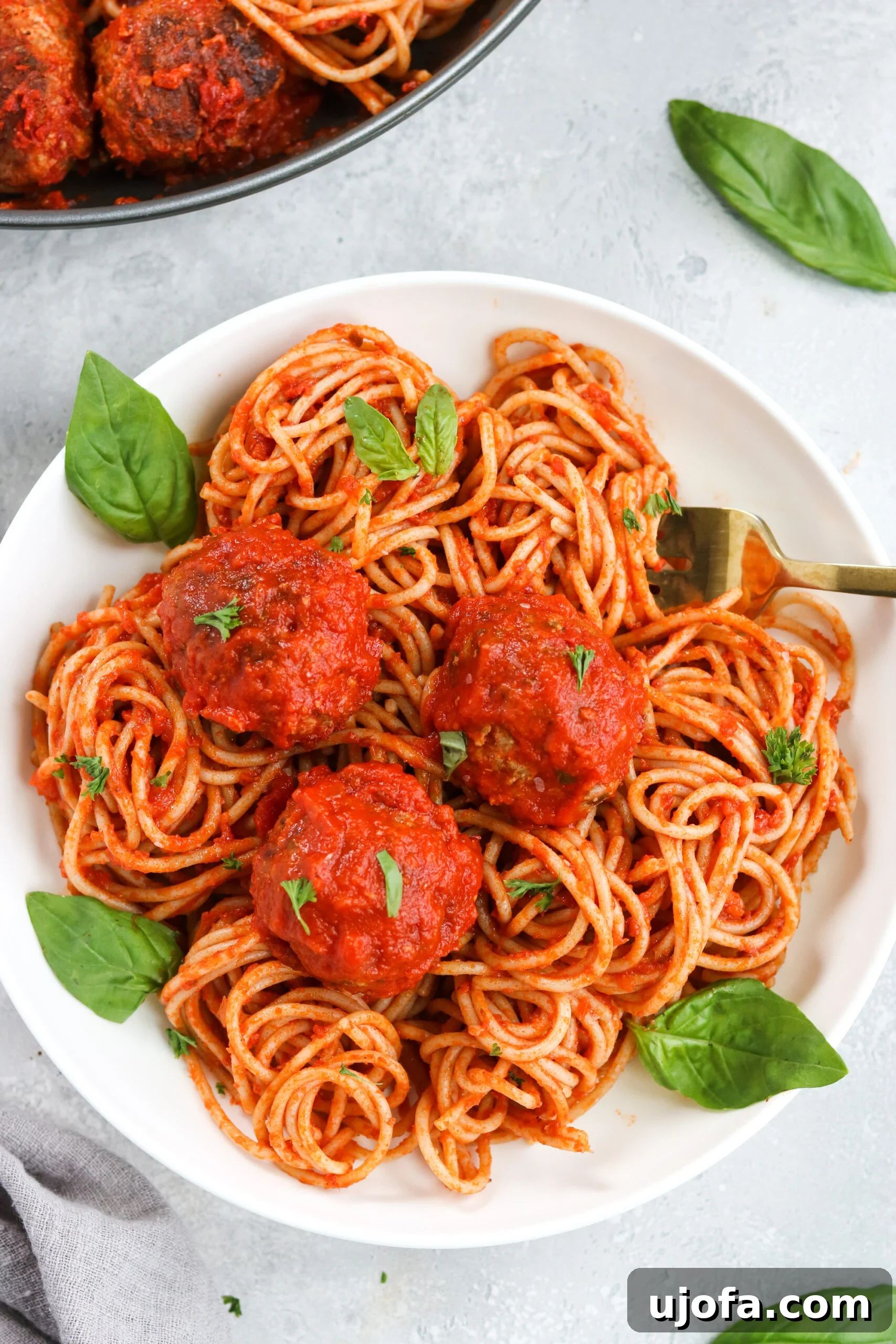 Gluten Free Italian Meatballs with Marinara sauce and gluten-free pasta, garnished with fresh basil.