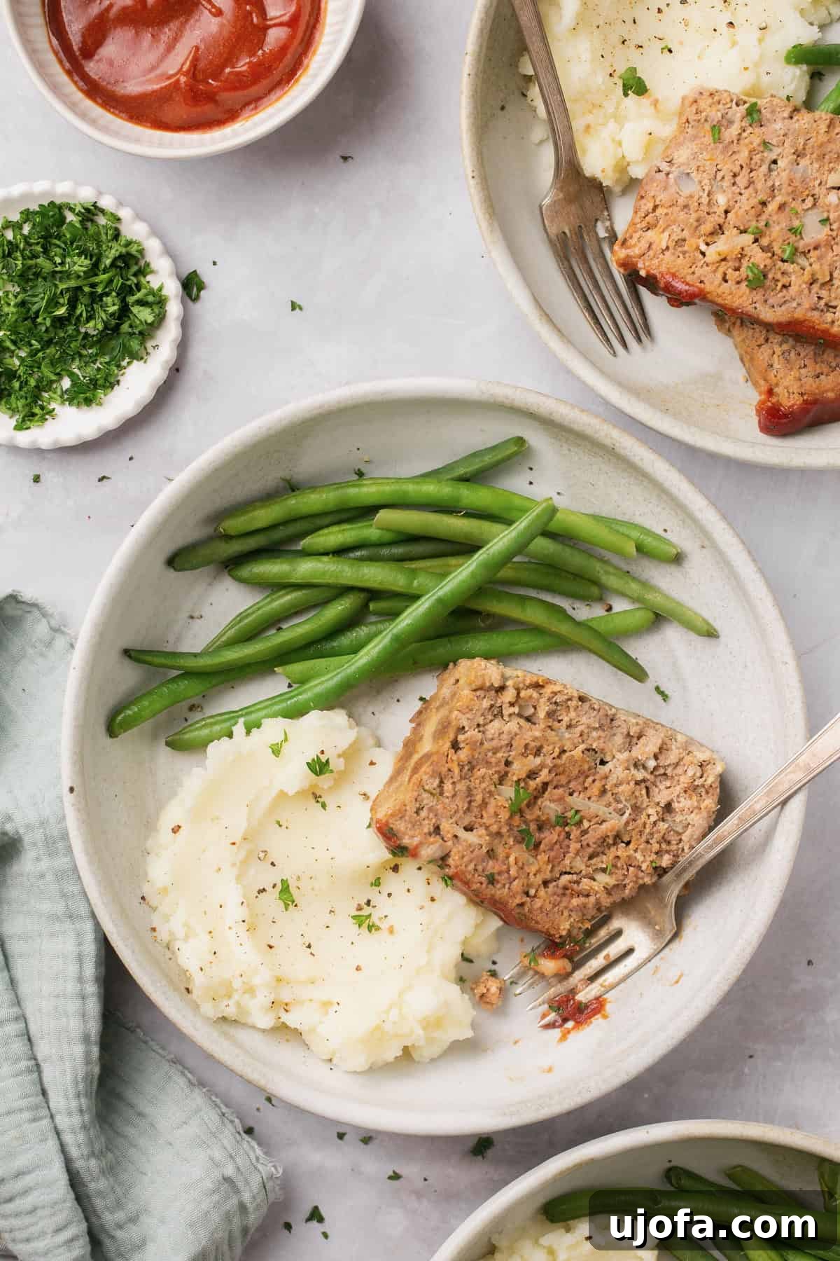 a plate topped with green beans, a slice of gluten free meatloaf, and mashed potatoes next to a fork 