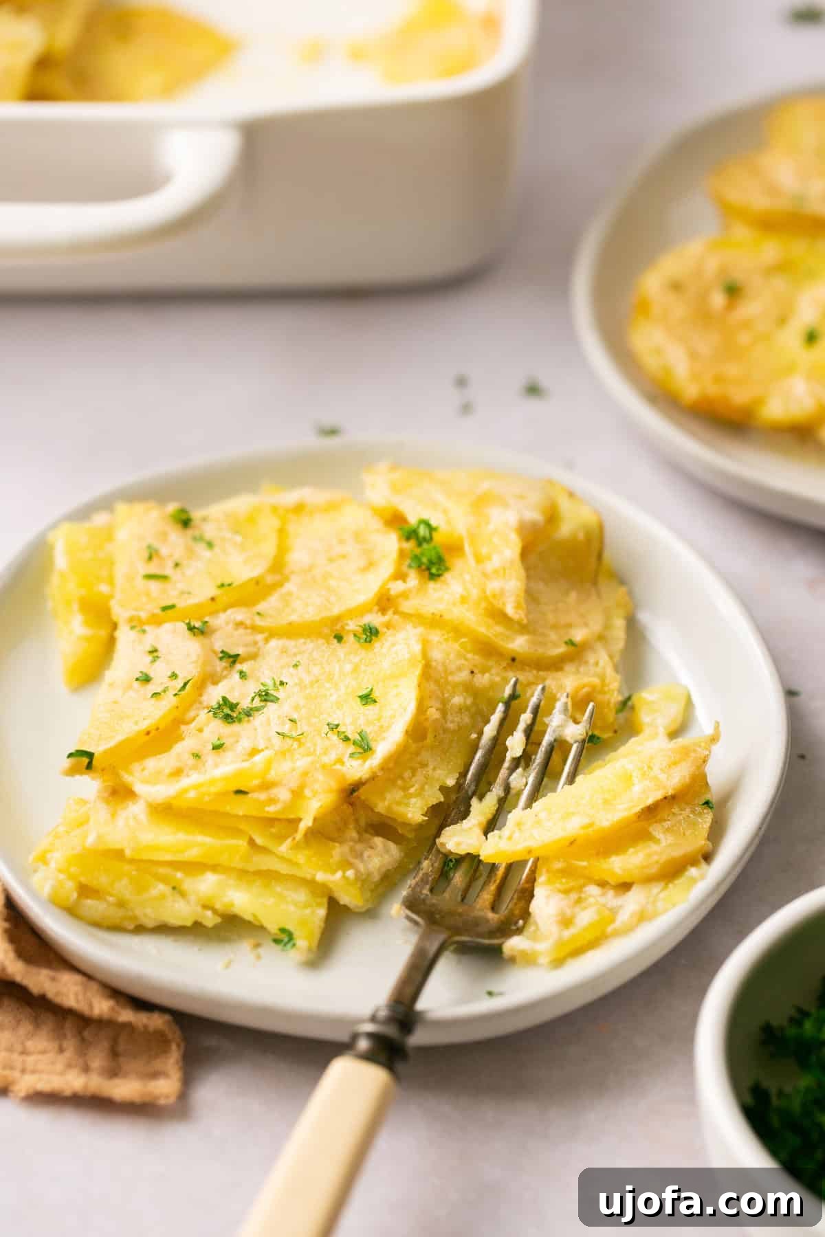 Simple Savory Gluten-Free Potato Gratin 8 a closeup shot of a slice of potatoes on a plate with a fork resting on the side