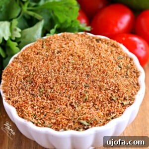 a bowl of gluten-free homemade taco seasoning with tomatoes, cilantro and avocado in the background